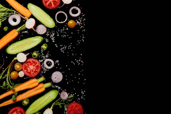 Vue de dessus des tranches de légumes frais avec sel dispersé isolé sur noir avec espace de copie — Photo de stock