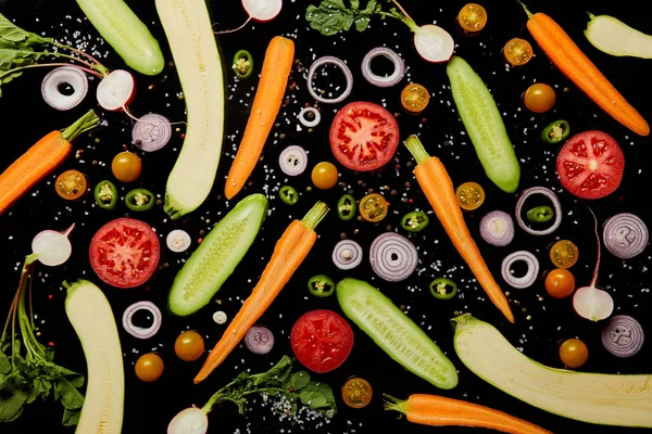 Вид сверху на свежие овощные ломтики с солью, выделенной на черном фоне — стоковое фото