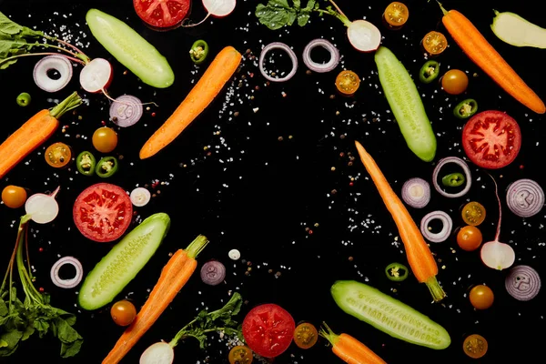 Vista dall'alto di fette di verdure fresche sparse con sale isolato su nero — Foto stock