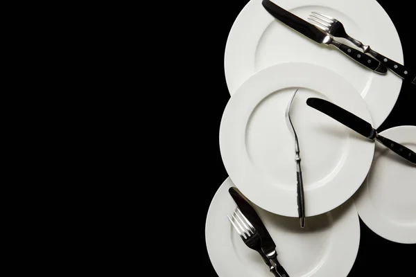 Top view of white round plates with cutlery isolated on black with copy space — Stock Photo