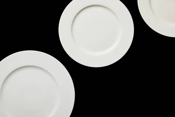 Top view of white empty round plates isolated on black — Stock Photo