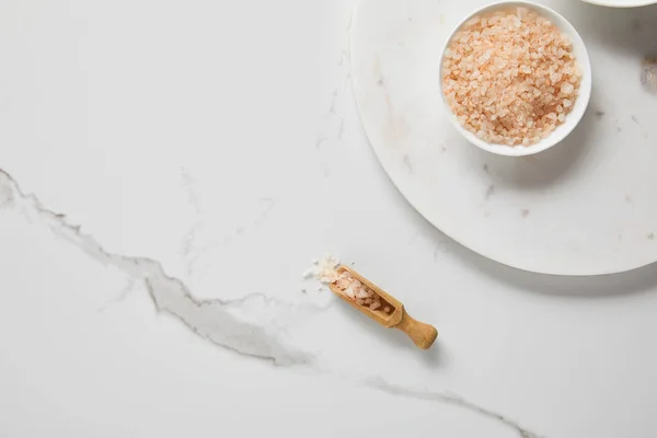 Top view of sea salt in bowl on marble table near wooden spatula — Stock Photo