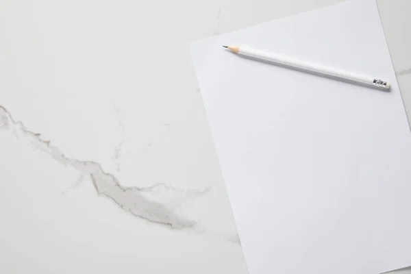 Вид сверху на белую пустую бумагу и карандаш на мраморном столе — стоковое фото