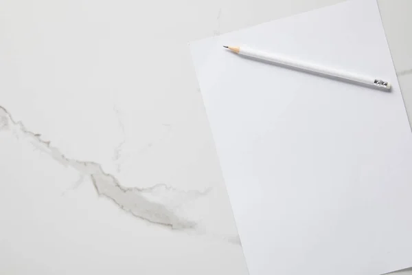 Vista superior de papel blanco vacío y lápiz sobre mesa de mármol - foto de stock