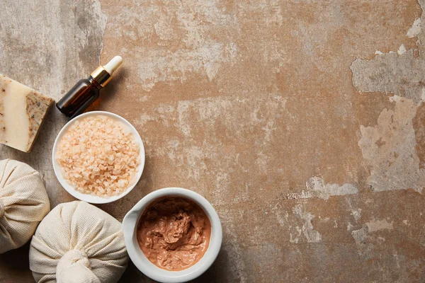 Top view of clay and sea salt in bowls near soap and oil on textured weathered surface — Stock Photo