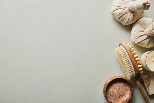 Vue du dessus de la poudre d'argile dans un bol en bois près de la brosse de massage, bougie sur fond blanc — Photo de stock