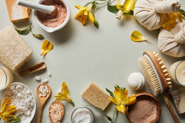 Vista dall'alto di cosmetici biologici e forniture di bellezza su sfondo bianco con candele e fiori gialli — Foto stock