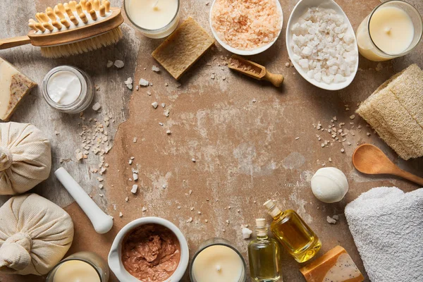 Draufsicht auf natürliche kosmetische Inhaltsstoffe und Schönheitsmittel in der Nähe von dekorativen Kerzen auf texturiertem verwittertem beigem Hintergrund — Stockfoto