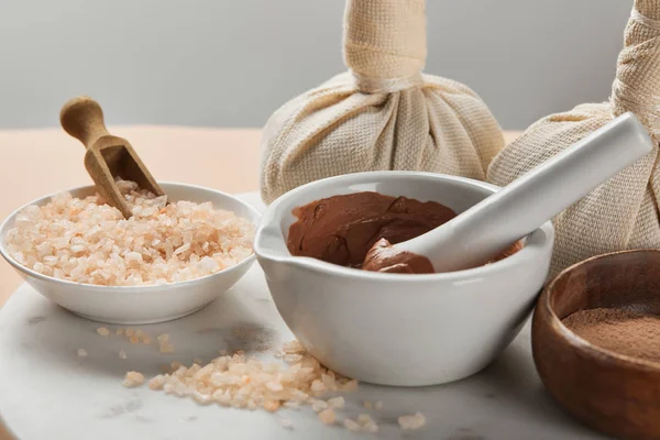 Clay and sea salt in bowls on marble surface isolated on grey — Stock Photo