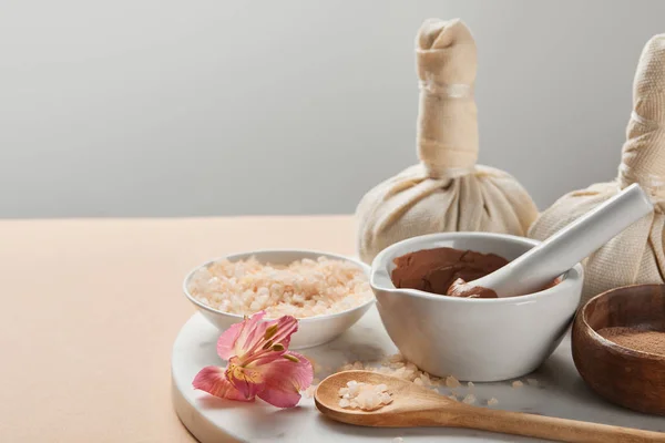 Argile et sel de mer dans des bols sur la surface de marbre avec fleur et décor isolé sur gris — Photo de stock