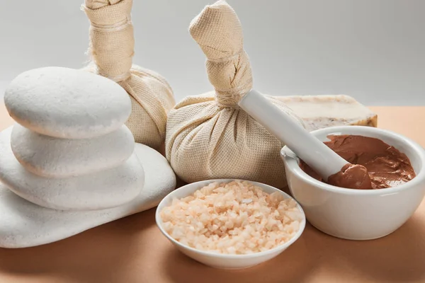 Sea salt, clay, stones and soap on beige table isolated on grey — Stock Photo