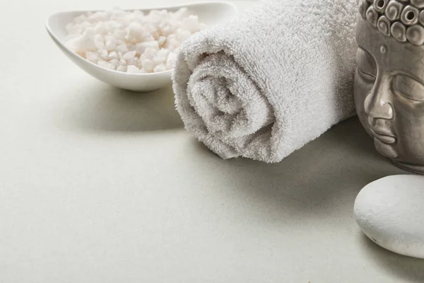 Морская соль в миске, хлопковое полотенце, камень и статуэтка Будды на белом фоне — стоковое фото