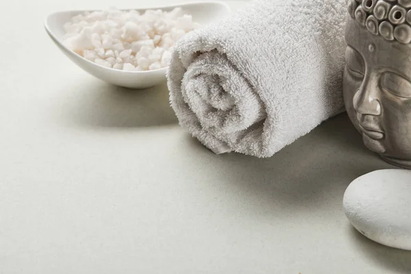 Sel de mer dans un bol, serviette de coton, pierre et figurine de Bouddha sur fond blanc — Photo de stock