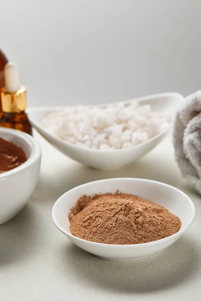 Selective focus of clay powder and sea salt in bowls isolated on grey — Stock Photo