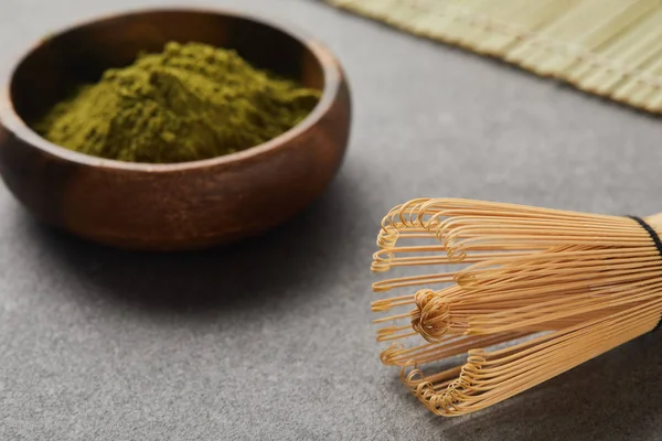 Selective focus of bamboo whisk and green matcha powder in wooden bowl — Stock Photo