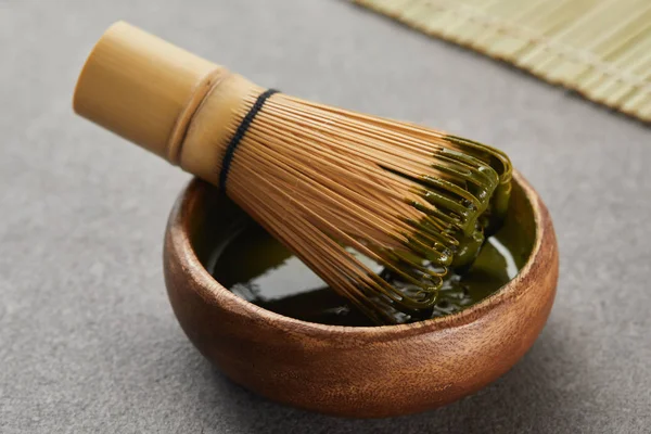 Selective focus of bamboo whisk in wooden bowl with green matcha powder — Stock Photo