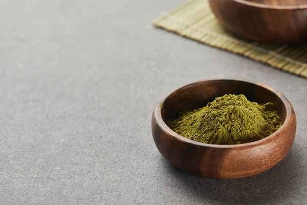 Messa a fuoco selettiva di polvere di matcha verde in ciotola di legno su tavolo grigio con spazio copia — Foto stock