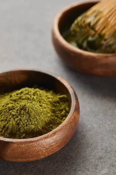 Selective focus of green matcha powder and bamboo whisk in wooden bowl — Stock Photo