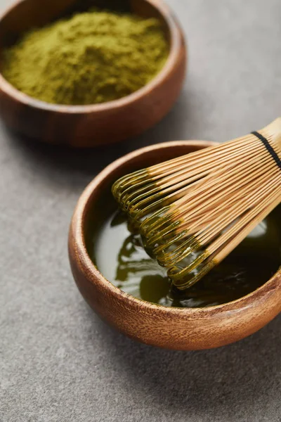 Selektiver Fokus von grünem Matcha-Pulver und Bambusbesen in Holzschüssel mit Tee — Stockfoto