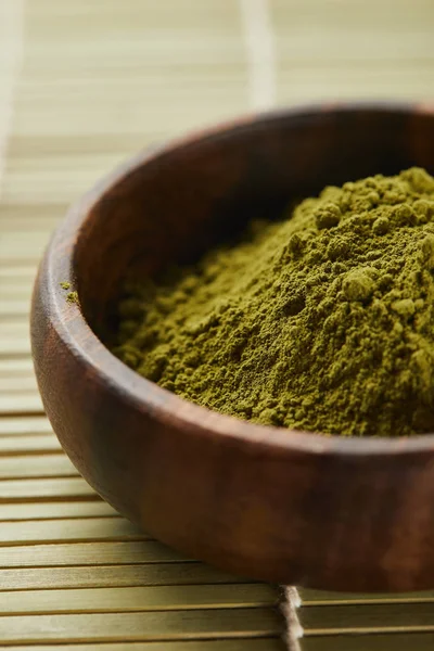 Selective focus of green matcha powder in wooden bowl on table mat — Stock Photo