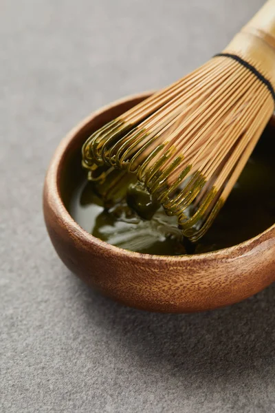 Batidor de bambú en un tazón de madera con té matcha - foto de stock