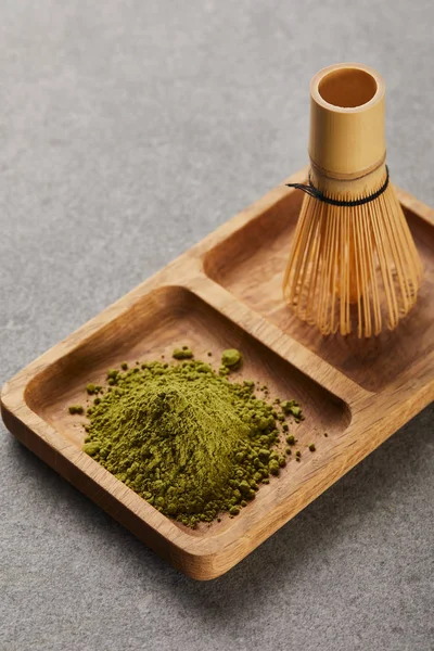 Vista de alto ângulo de pó matcha verde e batedor de bambu na placa de madeira — Fotografia de Stock