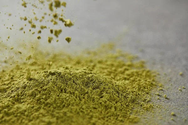 Foco seletivo de pó matcha verde derramando na mesa — Fotografia de Stock