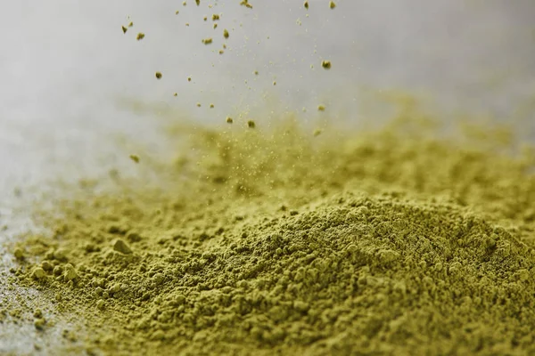 Selective focus of green matcha powder pouring on table — Stock Photo