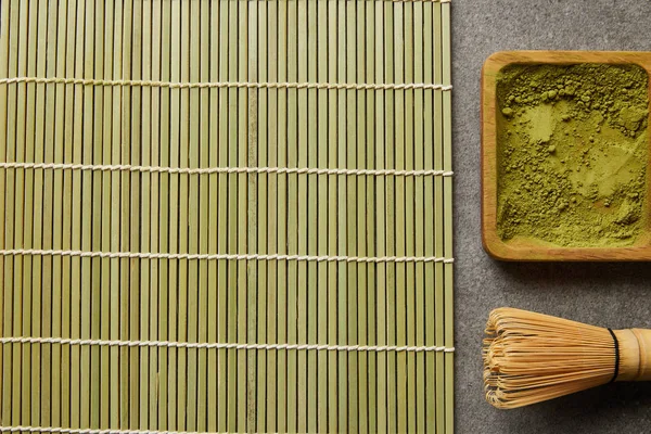 Vue de dessus de la poudre de matcha vert sur la planche en bois près du fouet de bambou et du tapis de table — Photo de stock