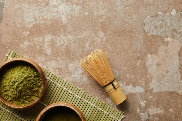 Vista dall'alto di polvere di matcha in ciotola di legno vicino a tè verde e frusta di bambù — Foto stock