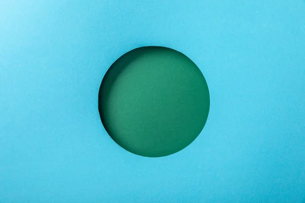 Голубой бумажный фон с зеленым круглым отверстием — стоковое фото
