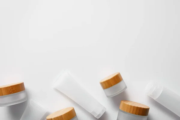 Vue de dessus de quelques pots vides et tubes à crème sur blanc — Photo de stock