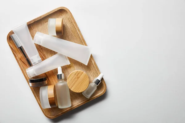 Abundância de recipientes cosméticos vazios na bandeja de madeira no branco — Fotografia de Stock