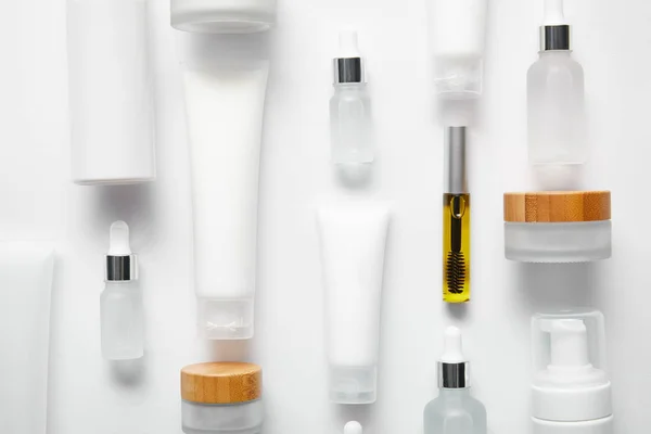 Pose plate de tubes à crème avec crème pour les mains, bouteille de mascara avec huile, bouteilles en verre cosmétique, distributeurs de cosmétiques et pots sur blanc — Photo de stock