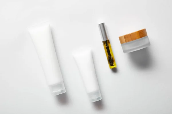 Top view of cream tubes with hand cream, empty jar and mascara bottle with oil on white — Stock Photo