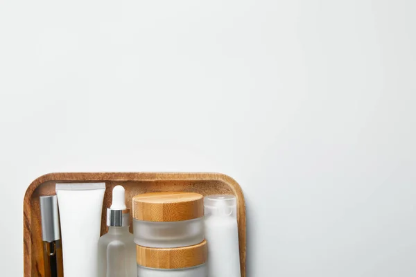 Top view of different cosmetic containers on wooden tray on white — Stock Photo