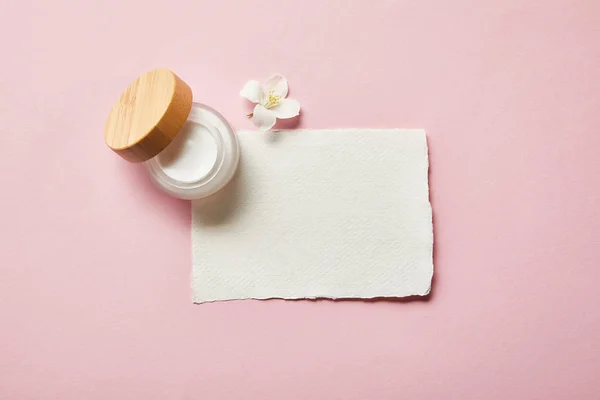 Vista dall'alto di vaso aperto con tappo in legno, pezzo di carta e fiore di gelsomino su rosa — Foto stock