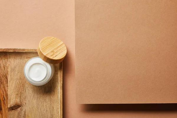 Top view of open jar with cream on wooden tray on brown — Stock Photo