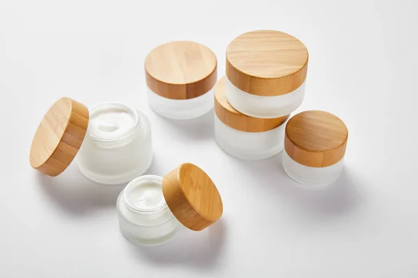 Open and closed jars with face cream and wooden caps on white — Stock Photo