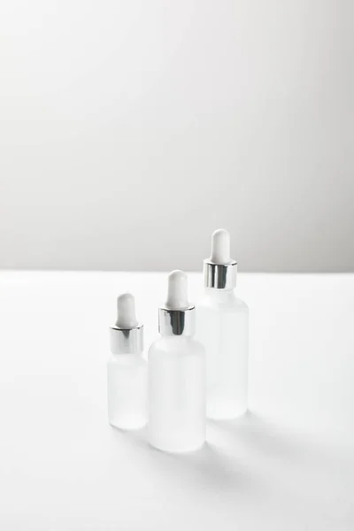 Botellas de vidrio de diferentes tamaños con suero en blanco - foto de stock