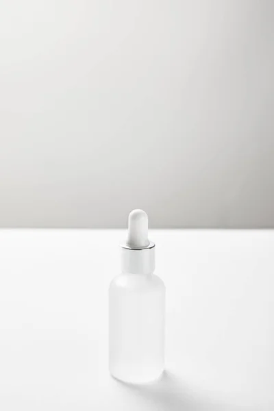 Bouteille en verre avec sérum cosmétique sur blanc — Photo de stock