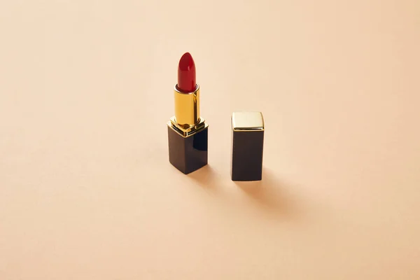 Single opened tube of red lipstick on beige with copy space — Stock Photo