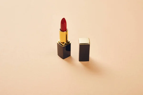 Único tubo abierto de lápiz labial rojo en beige con espacio para copiar - foto de stock