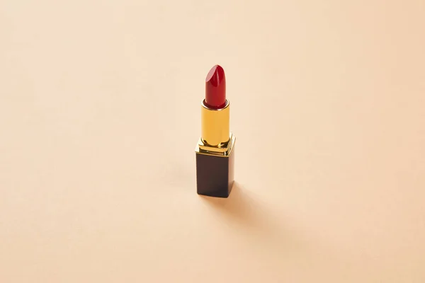 Single opened tube of red lipstick on beige — Stock Photo
