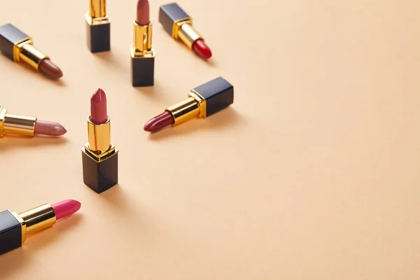Différentes nuances rouges de rouges à lèvres sur beige — Photo de stock