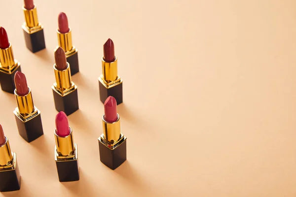 Red shades of lipsticks on beige with copy space — Stock Photo