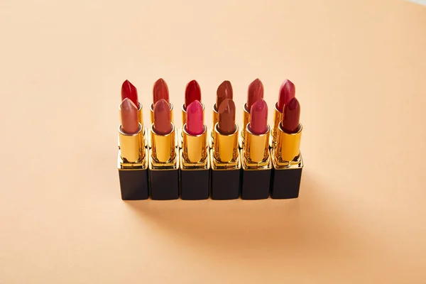 Différentes nuances rouges de rouge à lèvres en tubes sur beige — Photo de stock