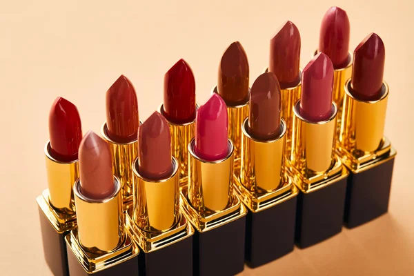 Nahaufnahme von roten Lippenstiftschattierungen in Tuben auf Beige — Stockfoto