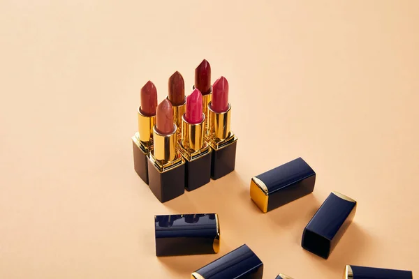 Different red shades of lipstick in tubes on beige — Stock Photo