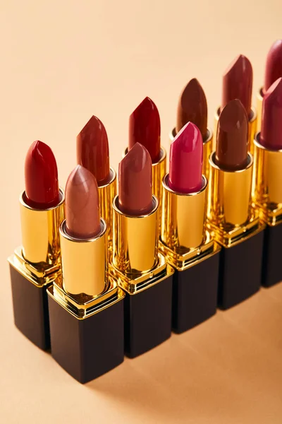 Closeup of various red shades of lipstick in tubes on beige — Stock Photo